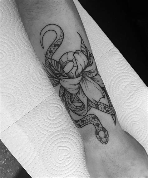 Tattoo no braço próximo ao pulso de flor e cobra em blackwork Tatuagem