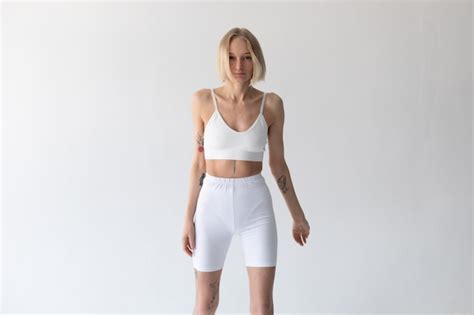 Une Fille Blonde Posant Sur Un Fond Blanc Dans Un Haut Et Des Leggings Photo Gratuite