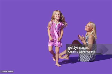 Portrait Playful Mother And Daughter In Striped Dresses Against Purple Background Stock Foto