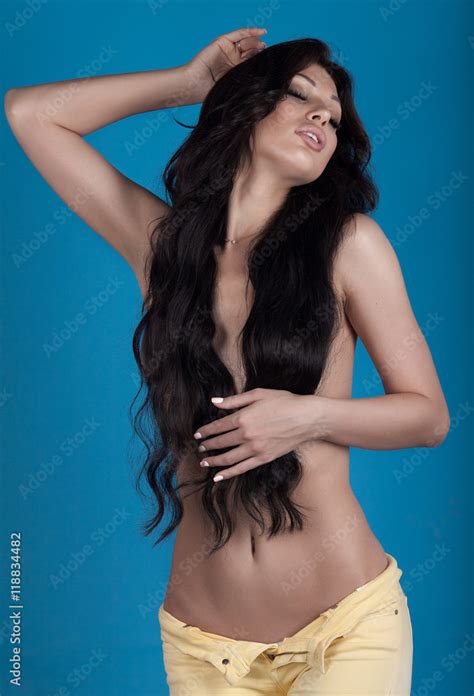 Sexy Naked Woman In Yellow Jeans Long Curly Black Hair On Blue