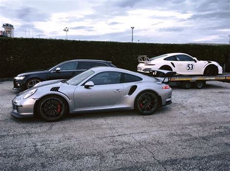 Two Porsches Parked In A Parking Lot Next To Each Other