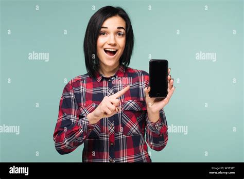 Surprised Happy Brunette Woman In Plaid Shirt Showing Blank Smartphone