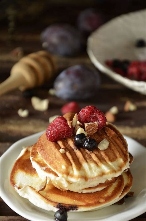 A Stack Of Pancakes Topped With Berries And Nuts