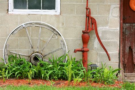 Antique Wooden Wagon Wheel And Water Pump By Barn Stock Image Image