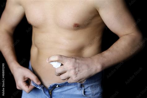 Man In Unbuttoned Jeans With Naked Torso Disinfecting His Body On Black