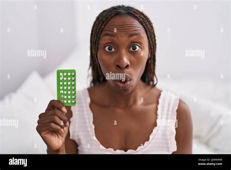 African American Woman Holding Birth Control Pills Scared And Amazed