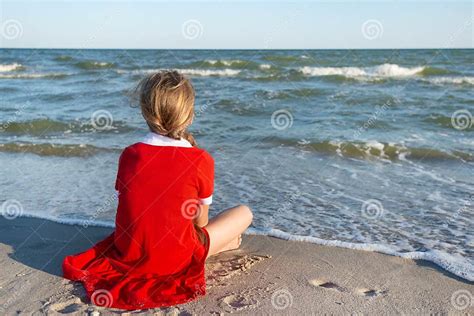 Adolescente En Robe Rouge Assise Sur La Plage Rêvant Et Regardant La