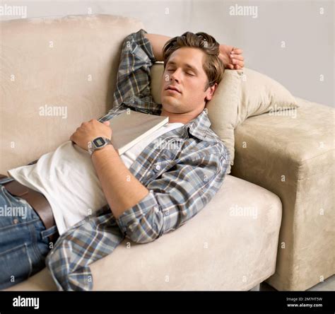 Falling Asleep While Reading A Handsome Young Man Sleeping On The Couch While Holding A Book