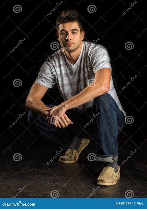 Handsome Man Casually Posed Kneeling Down Staring At Camera Stock Image