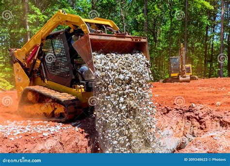 During Construction A Skid Steer Loader Unloads Gravel From An