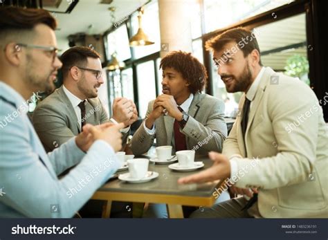 Men Are Sitting At Table In Modern Cafe Talk About Work Ad