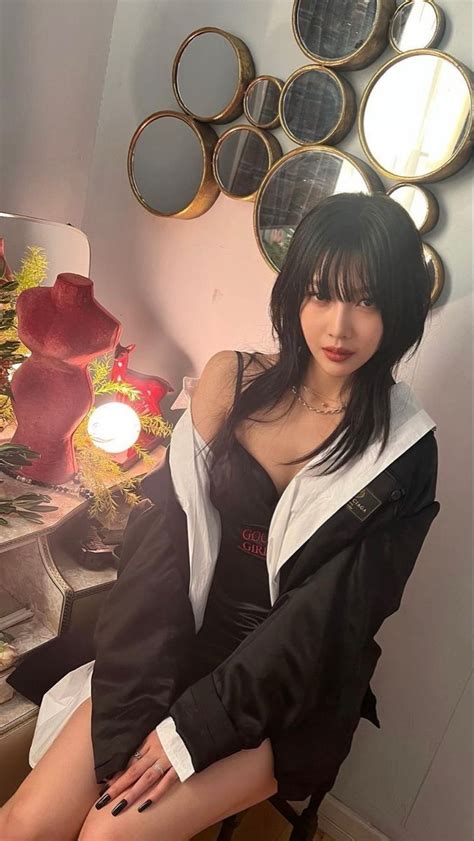 A Woman Sitting On Top Of A Wooden Chair In Front Of A Wall With Mirrors