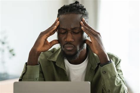 Infeliz freelancer masculino negro tocando a cabeça sofrendo de dor de