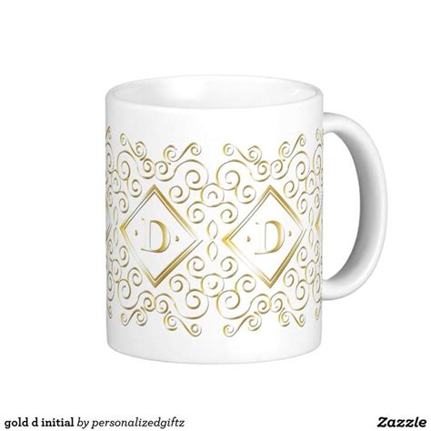 A White And Gold Coffee Mug With The Letter D On It S Front Side