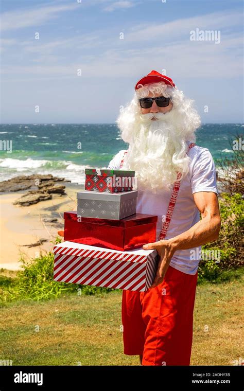 Santa Claus holds gift boxes with the ocean on backgraund. Australia ...