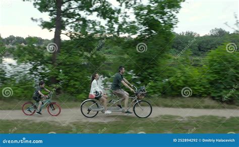 Married Couple With A Child Rides A Two Person Tandem Bike Along The