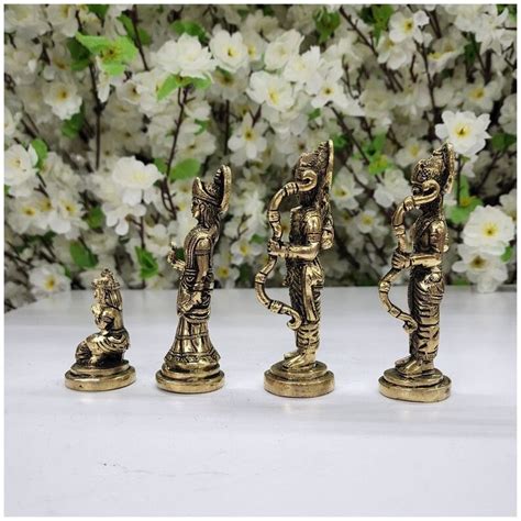 four brass figurines sitting next to each other on a white table with flowers in the background