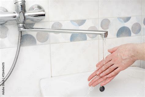 Washing Hands With Liquid Soap In A Bottle Under The Faucet In The