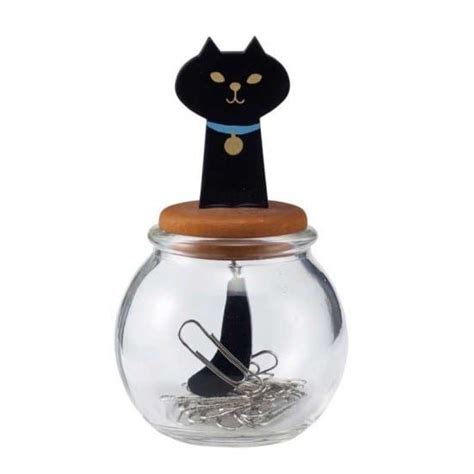 A Cat Figurine Sitting On Top Of A Glass Jar Filled With Paper Clips