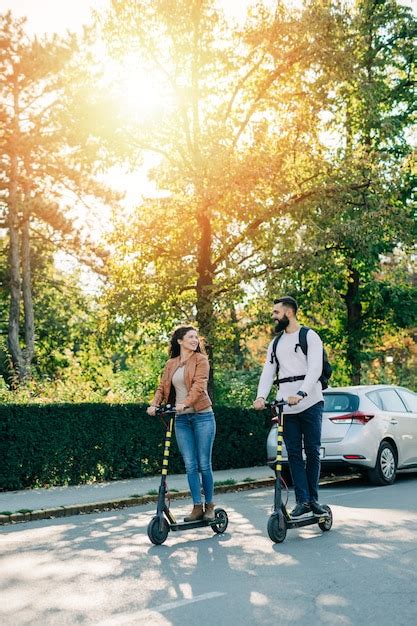 Premium Photo Happy Young Couple Enjoying Together While Riding Electric Scooters On City Street