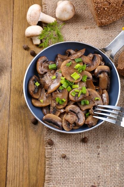 Köstliche gebratene pilze in der pfanne auf dem tisch in der nähe