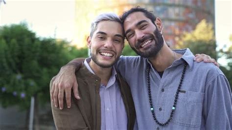 Portrait Of Lovely Gay Couple Embracing Each Other Happy Together And Smiling In The City