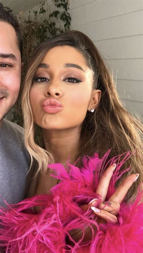 a man and woman posing for the camera with pink feathers on their arms ...