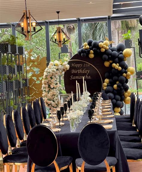 A Black And Gold Birthday Party Setup With Balloons Flowers And