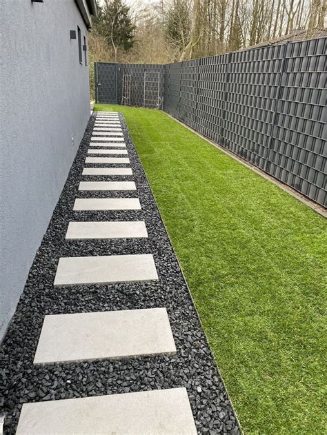 A Stone Path In The Grass Between Two Buildings