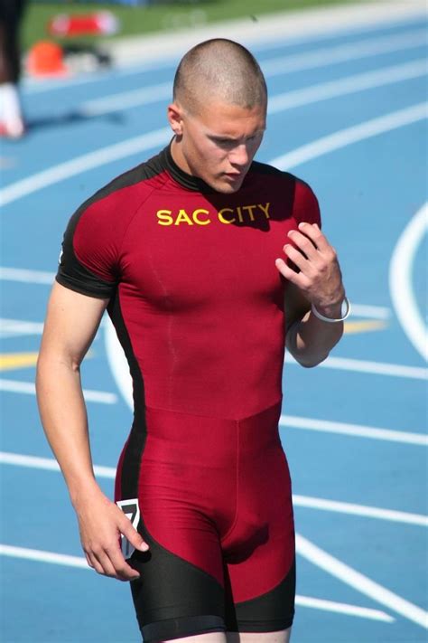 A Man In A Red And Black Suit Standing On A Track With His Hands Together