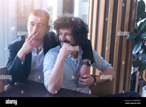 Two Gay Male Friends Hugging In A Cafe Smiling And Having A Cigarette LGBT And Love Concept