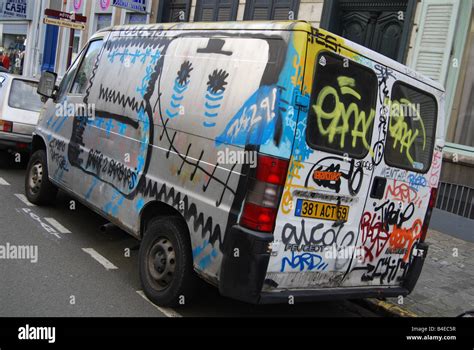 Urban street scene with vandalised graffiti covered minivan parked ...