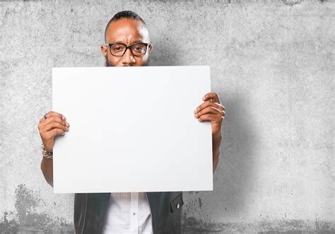 Free Photo Guy Holding A Blank Poster With Wall Background