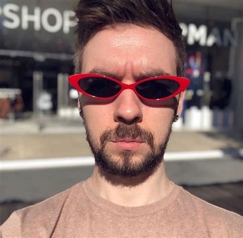 A Man Wearing Red Sunglasses Standing In Front Of A Store