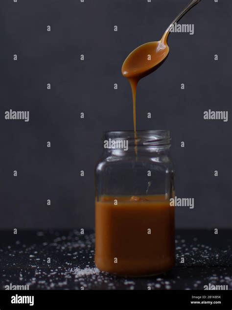 Salted Caramel Sauce Dripping From A Spoon Into A Glass Jar Caramel