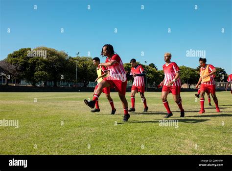 Male Multiracial Players Wearing Red Uniforms Running And Exercising