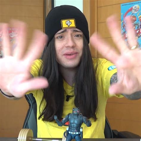 A Man With Long Hair Wearing A Beanie And Holding His Hands Up In Front