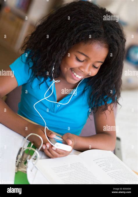 Young Girl Distracted From Her Homework Playing With An Mp3 Player