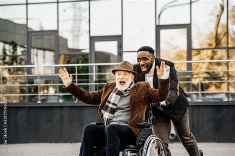 Happy Senior Disabled Man In Wheelchair And African American Man Having