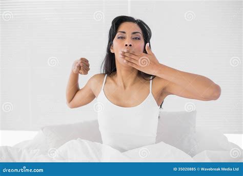 Attractive Young Woman Stretching Out And Yawning While Sitting On Her