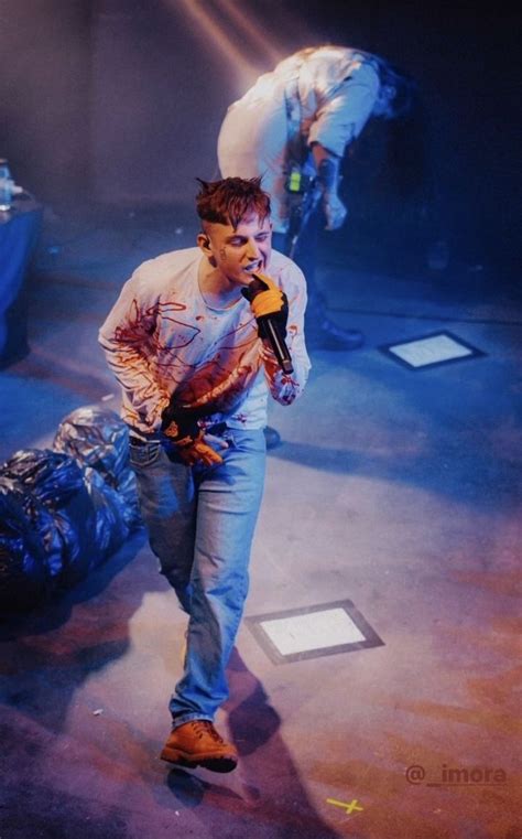 A Man Walking Across A Stage With A Microphone In His Hand And Another