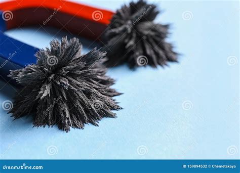 Horseshoe Magnet With Iron Filings On Blue Background Closeup Stock