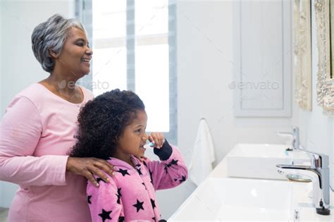 Grandmother And Granddaughter Brushing Teeth In The Bathroom Stock