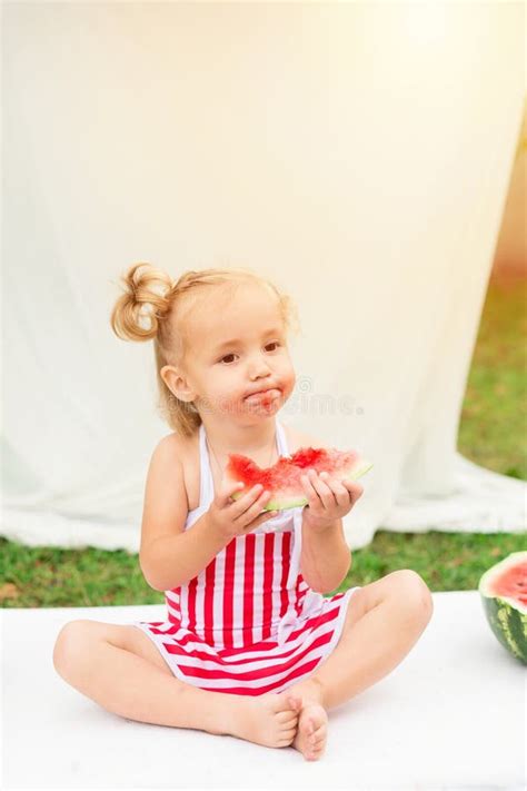 Little Girl With A Big Watermelon On A White Mattress In The Garden