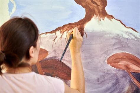 Mão de artista feminina segura pincel e desenha paisagem abstrata da