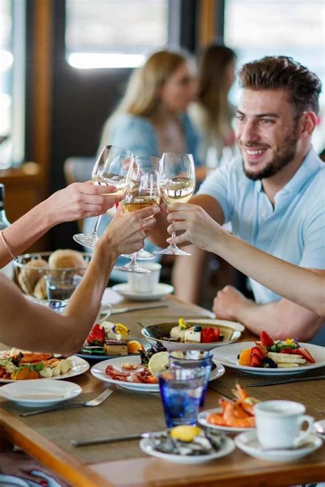 Two People Toasting With Wine Glasses At A Table Full Of Food And