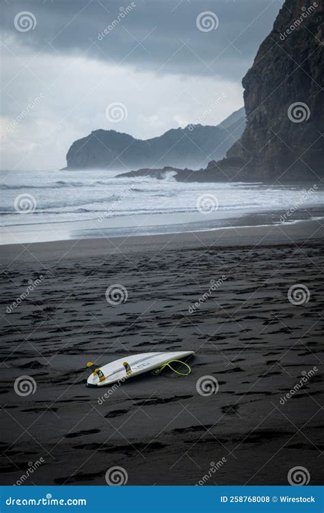 Surfing Board at the Rocky Coast in Piha, New Zealand Stock Photo ...