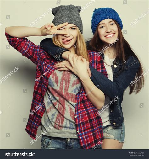 Two Young Girl Friends Standing Together And Having Fun Showing Signs