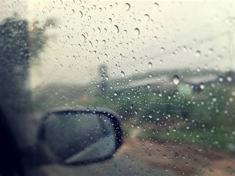 Rain Drops On The Car Glass Window With Road In Rainy Season Abstract