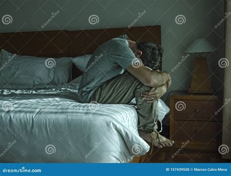 Dramatic Lifestyle Portrait Of Man Sitting Depressed On Bed Crying